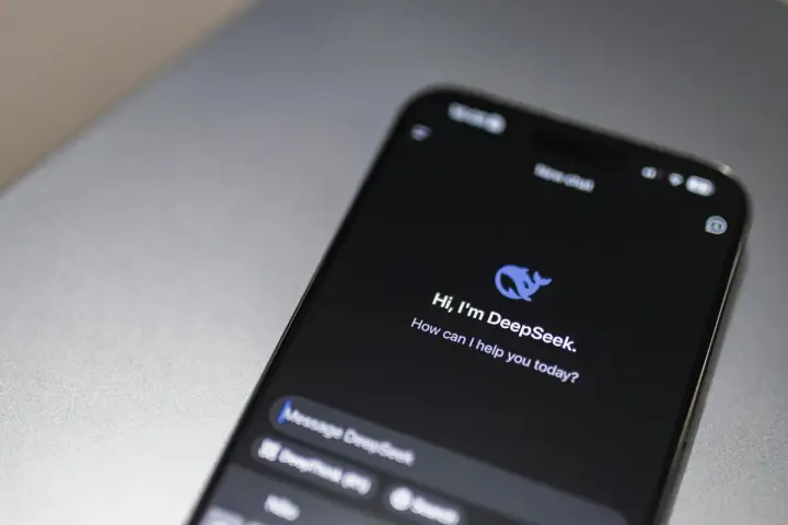 Celular exibindo a tela inicial do aplicativo DeepSeek sobre uma mesa cinza